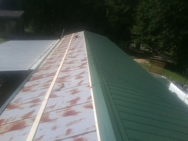 Old rusted panels beside newly installed green metal roofing — Wind Damage Roof Repair by Roofing Brothers in Franksville