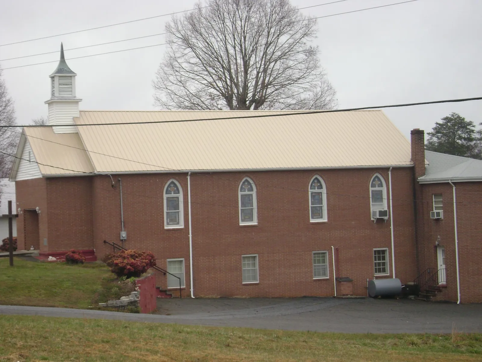 New tan metal roof on a brick church with a white steeple in Franksville