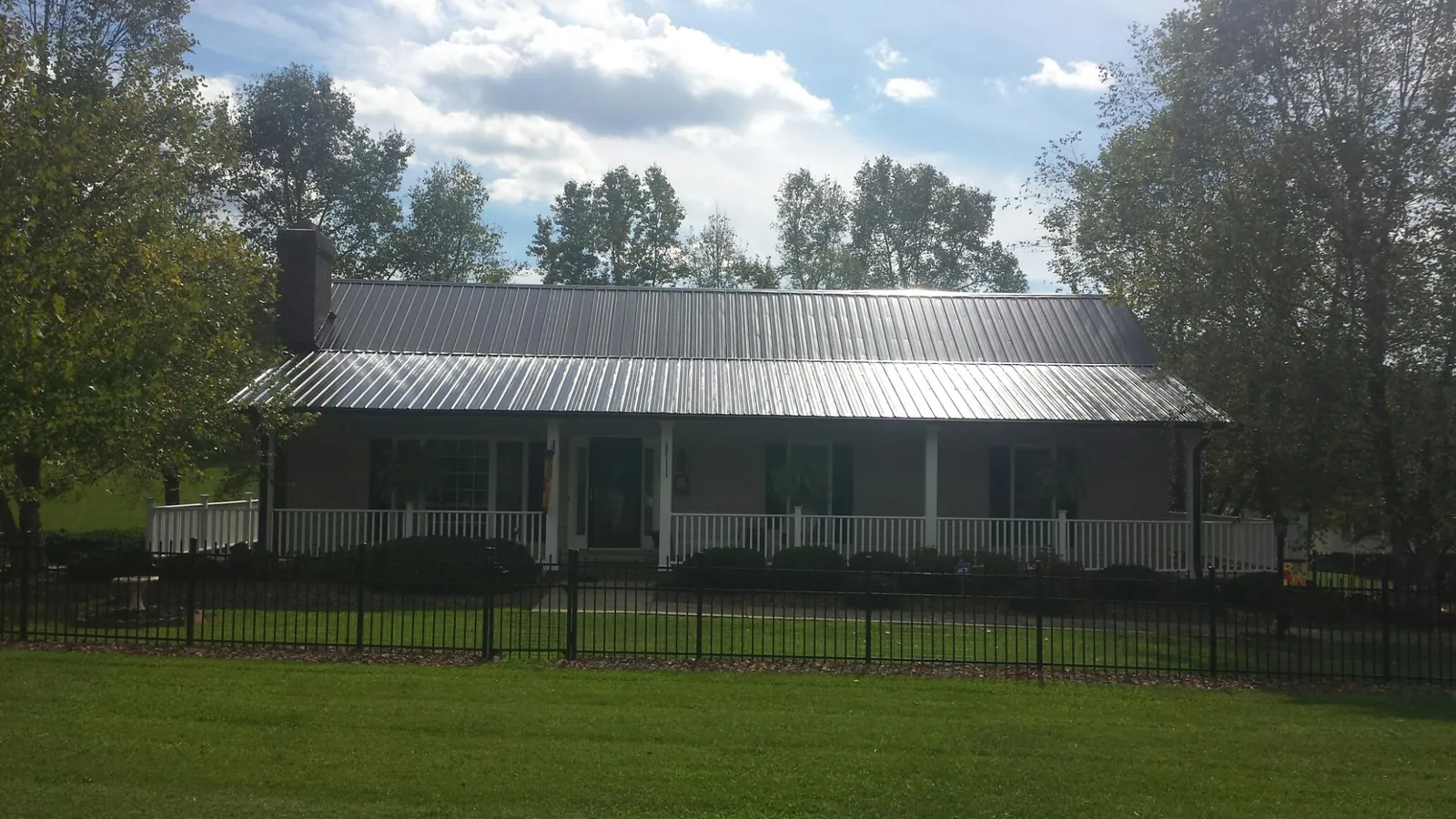 Gray metal roof on a brick ranch with a full width front porch — Gutter Guard Installation work by our crew in Franksville