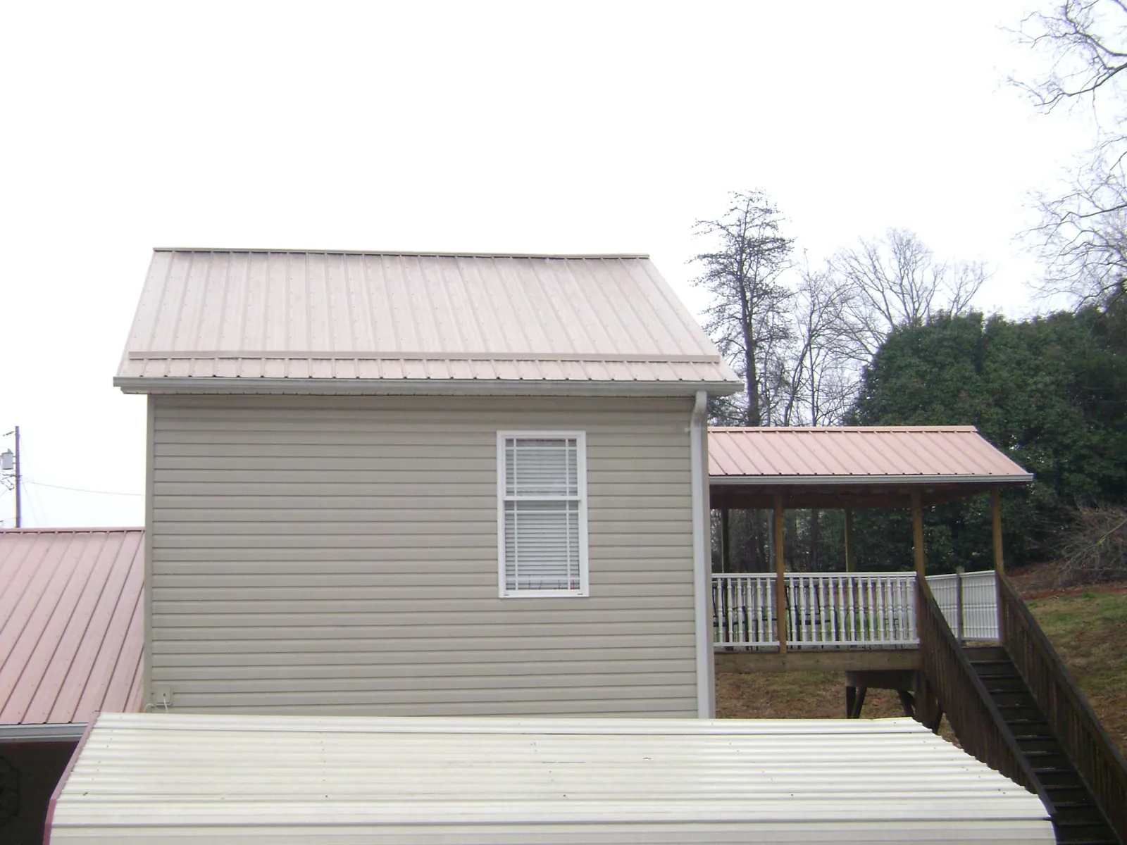 Tan metal roofs on a two story addition and attached porch, from a Roof Replacement job in Franksville