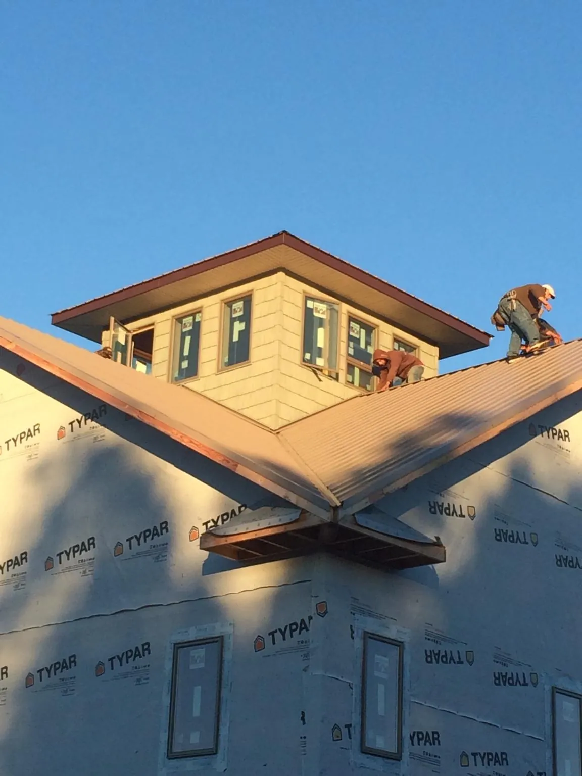Roofers working around a rooftop cupola on a new metal roof at sunset — Roof Waterproofing in Franksville by Roofing Brothers
